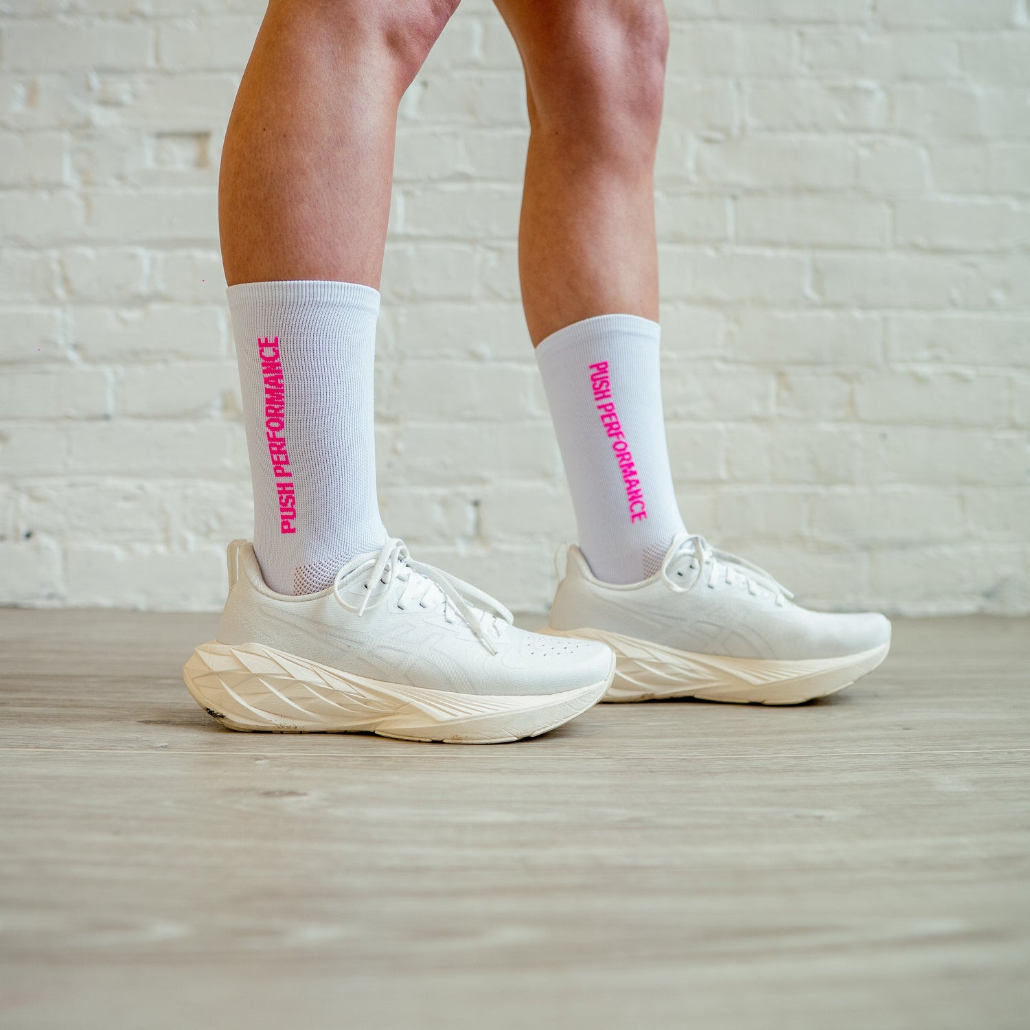 Push Performance endurance sock in white with hot pink accents, styled with trainers for race-ready fit