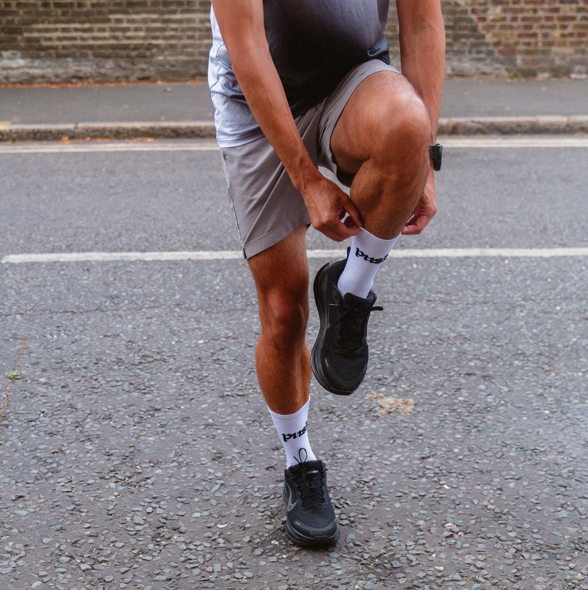 A close-up of a person pulling up white push performance running socks.