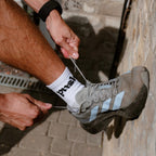runner tying shoe laces while wearing white quarter length running socks
