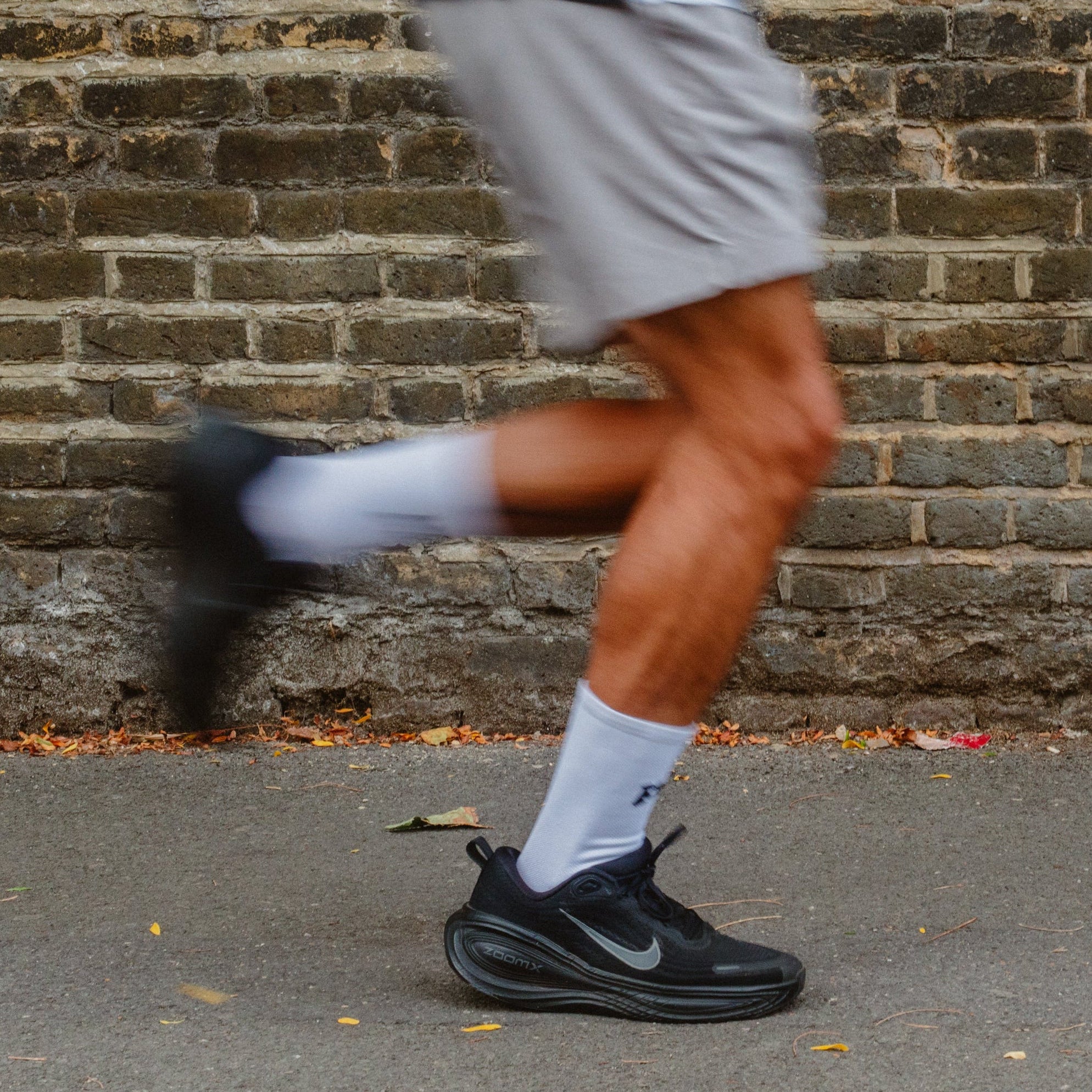 A close-up of a person running in white performance running socks.