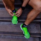 Person wearing bright green running shoes with push performance black quarter length running socks