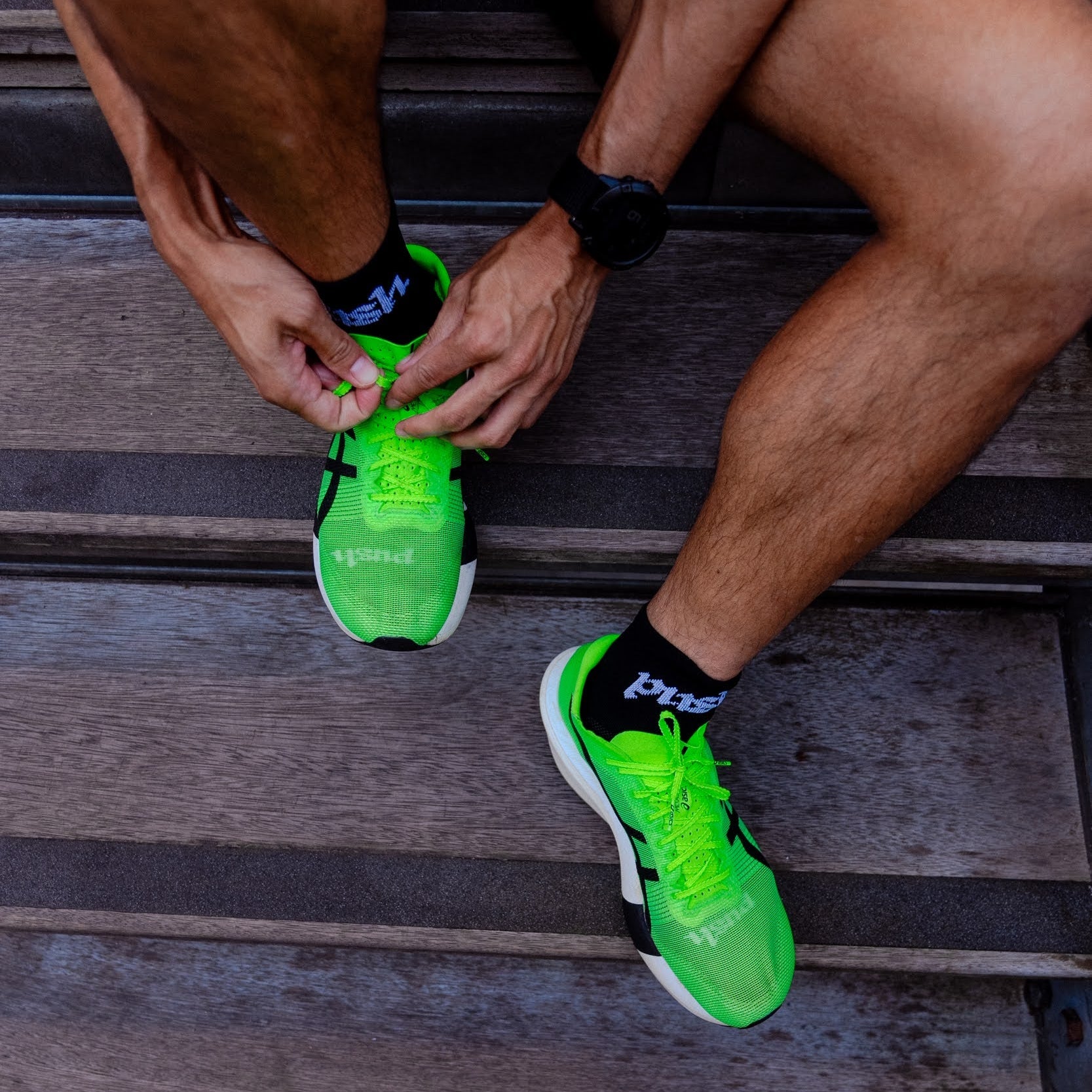 Person wearing bright green running shoes with black quarter length running socks