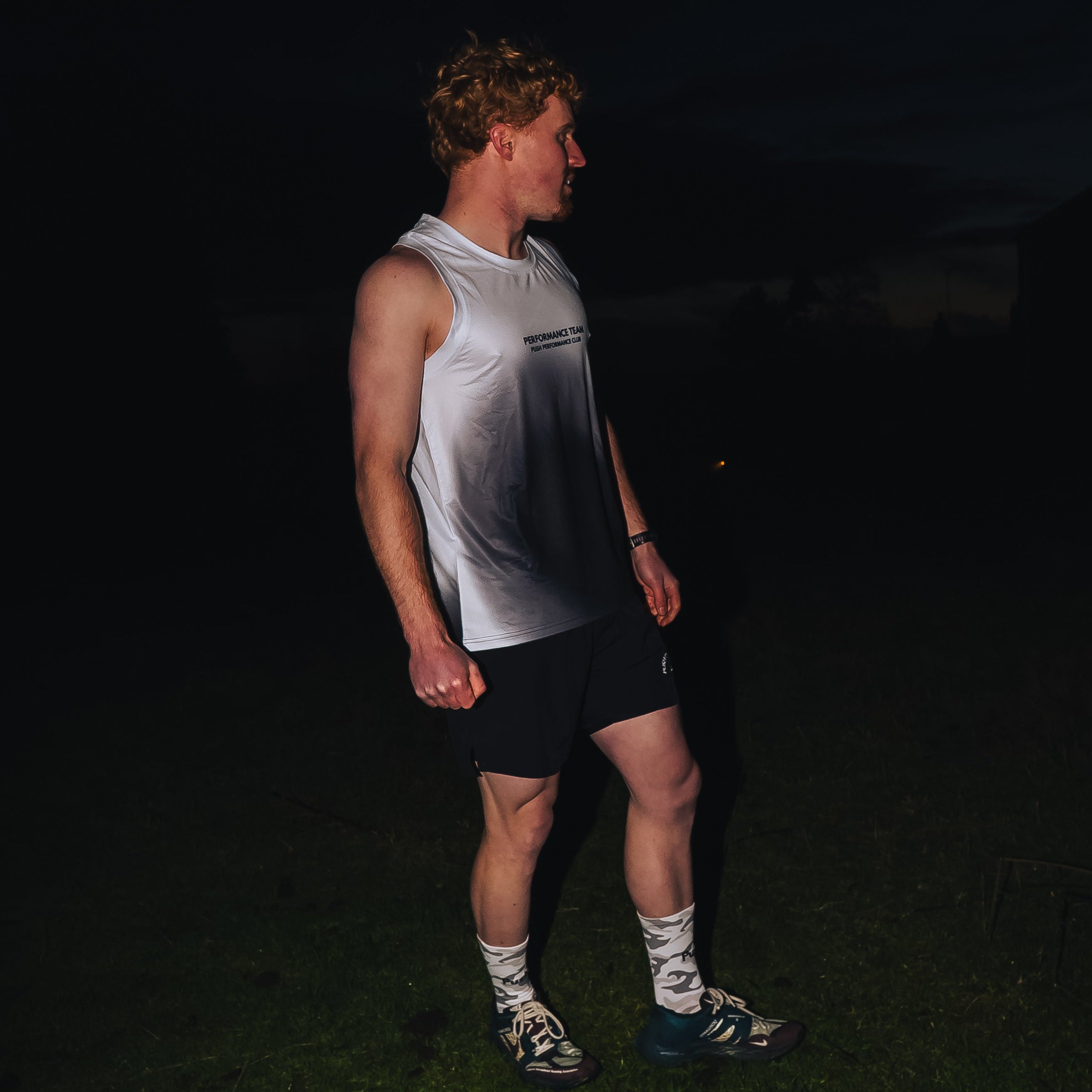 white black mens running vest being worn by a runner at night time. 