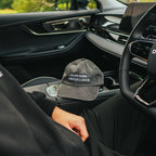 Person sitting inside a car with a cap on the dashboard