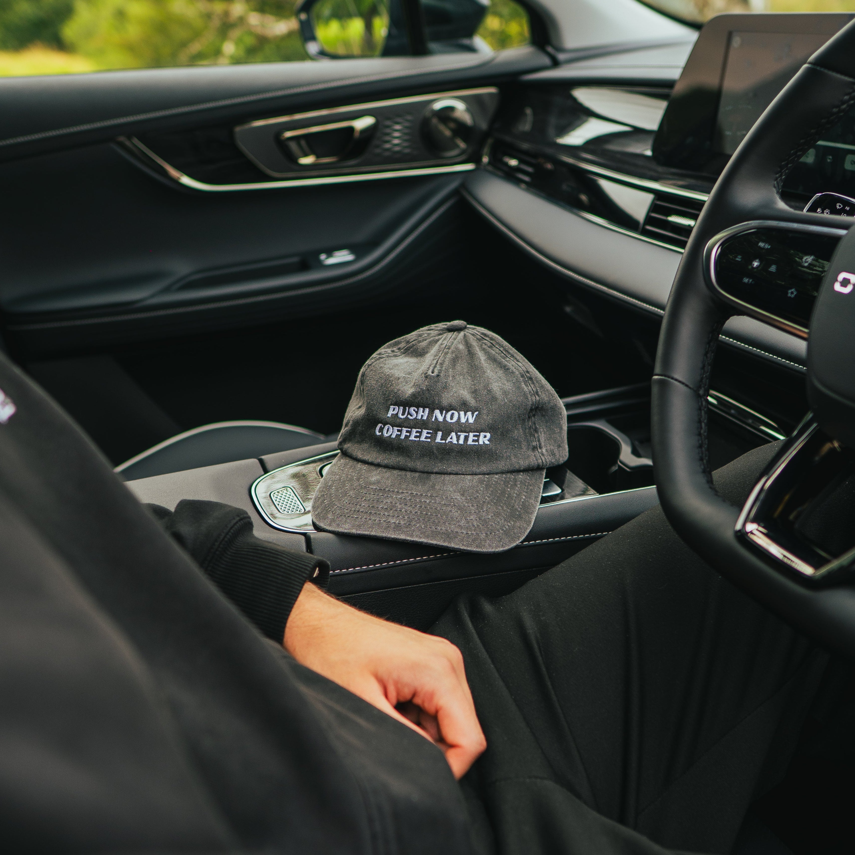 Person sitting inside a car with a cap on the dashboard