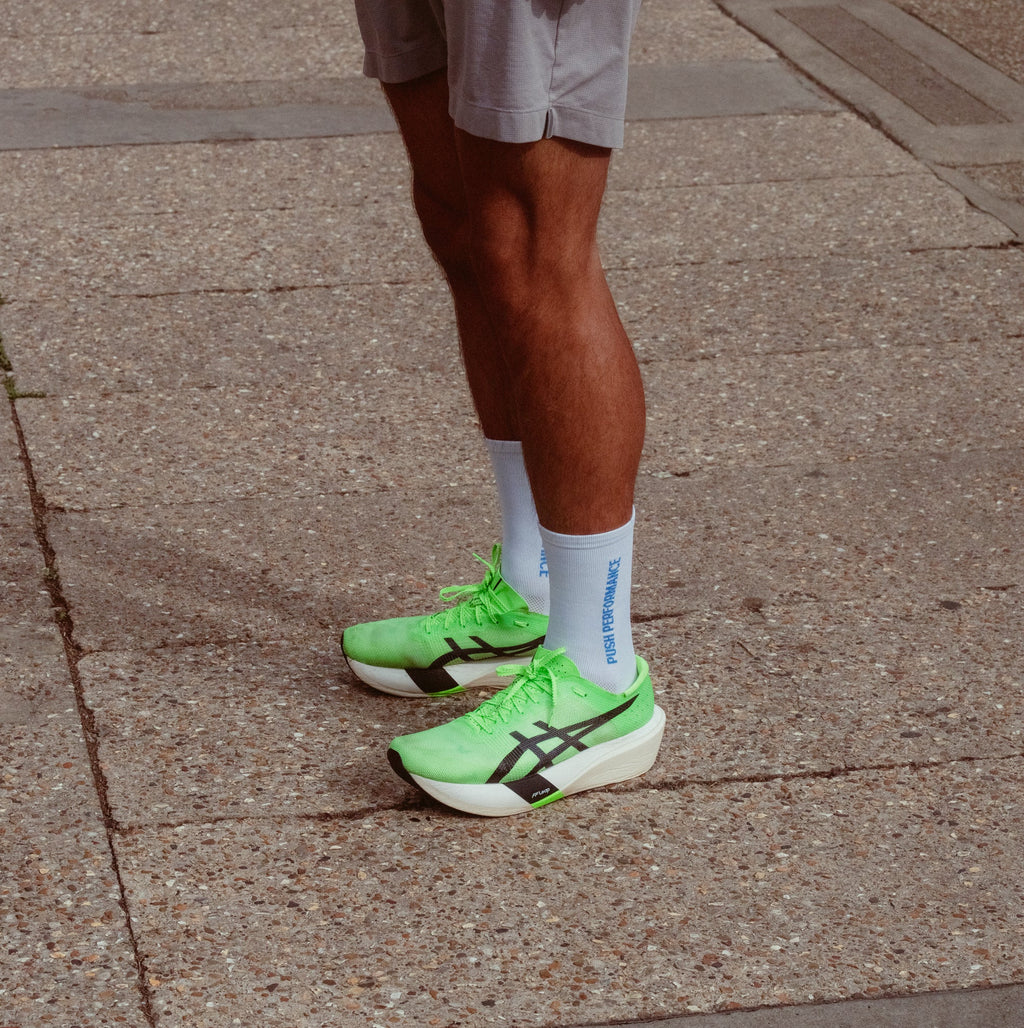 A close-up of a person wearing white and blue push performance running socks.