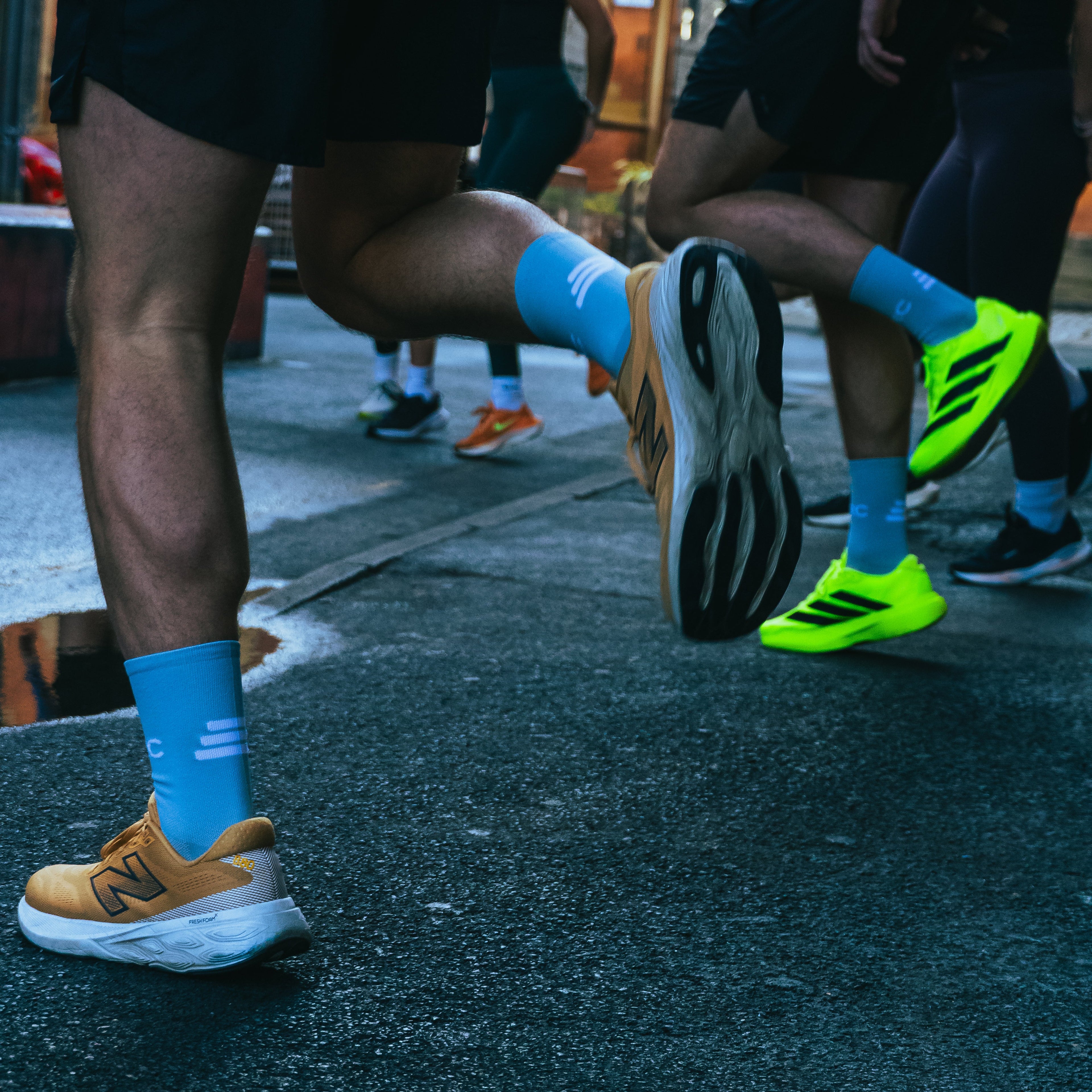 Close-up of runners' feet with colorful shoes and socks on a road in TMRC socks.