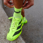 A close-up of a person pulling up bright neon yellow push performance running socks.