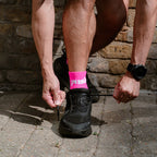 runner tying shoelaces while wearing pink quarter length running socks