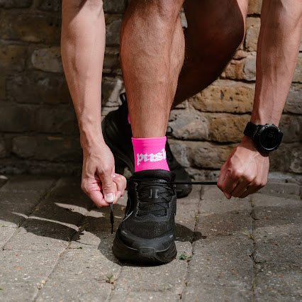 runner tying shoelaces while wearing pink quarter length running socks