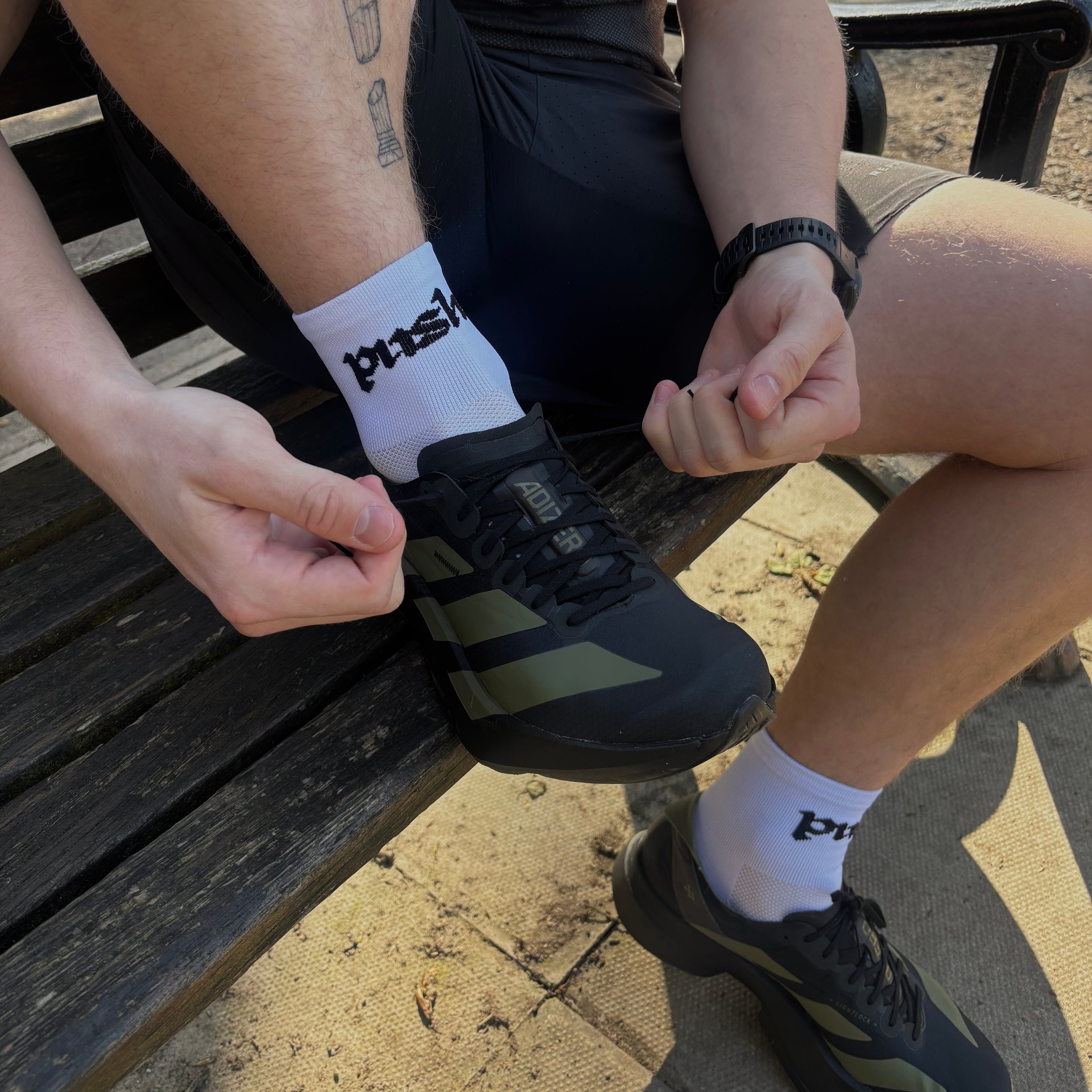 runner sat on bench putting on running shoes wearing white running socks 