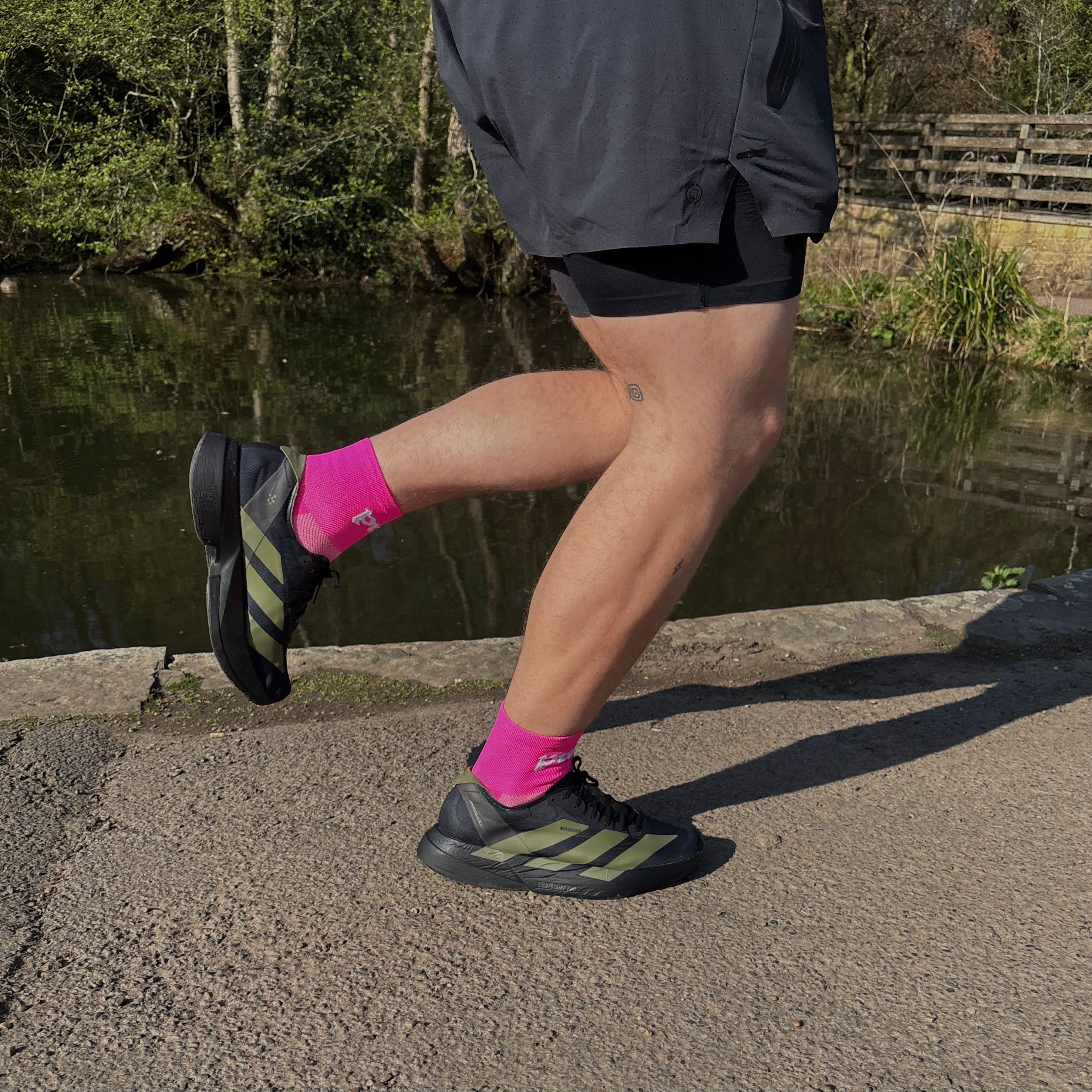 person running past a pond wearing pink running socks 