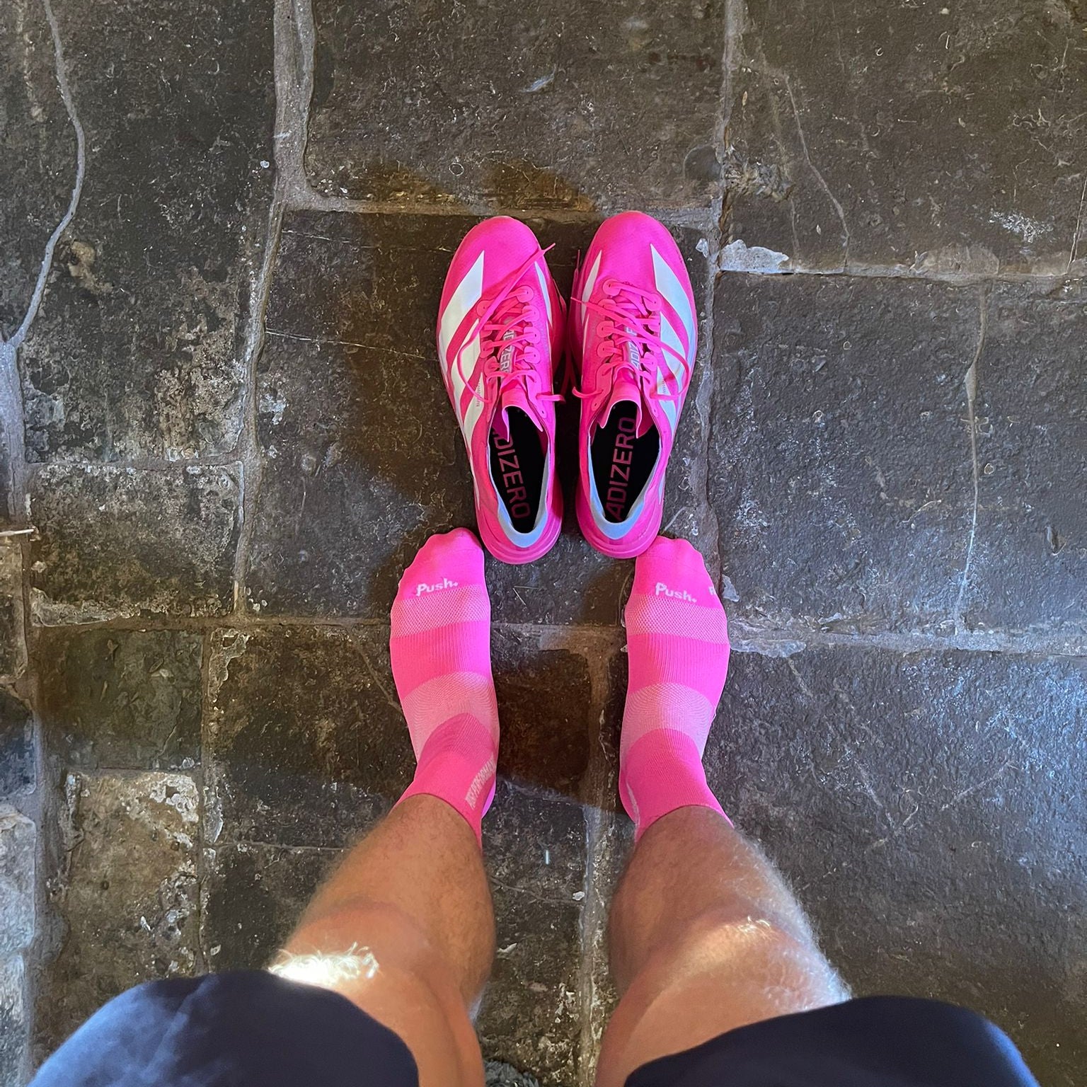 Person wearing pink athletic shoes on a stone floor