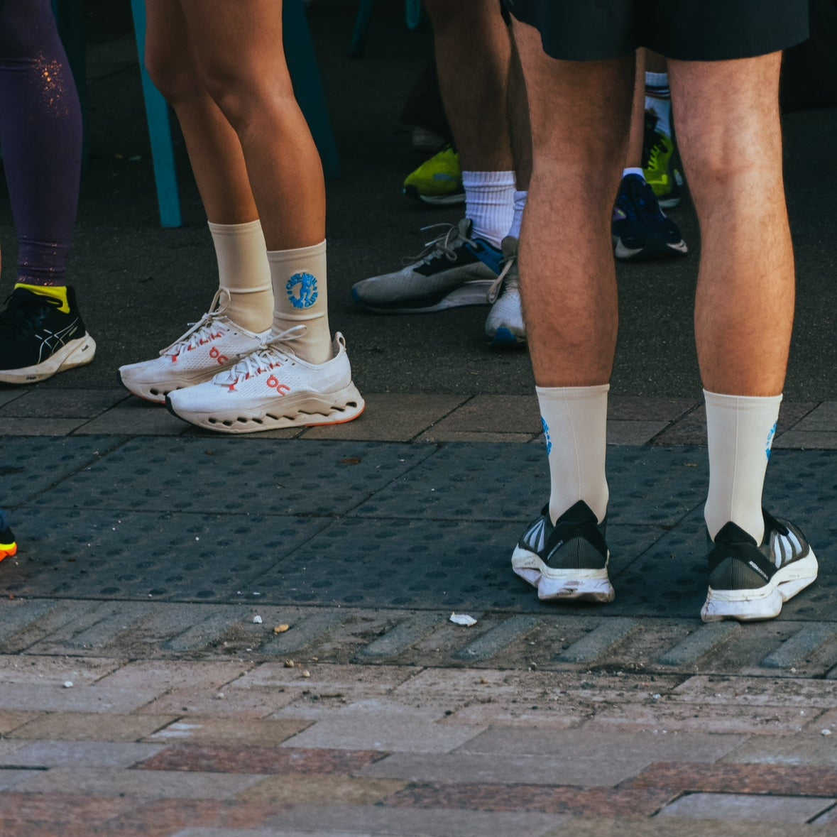 Close-up of runner legs wearing performance socks and shoes on a pavement.