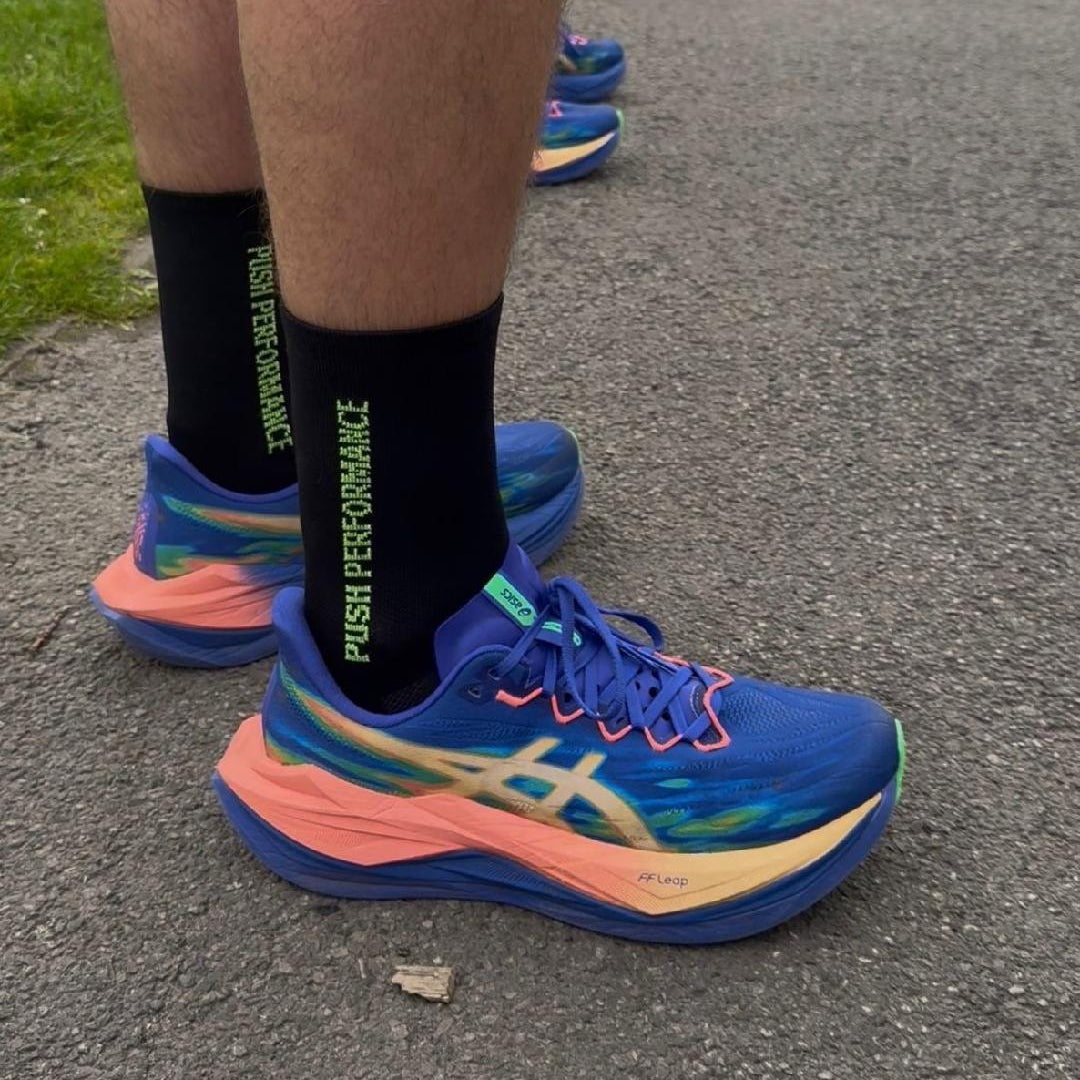 runner wearing blue running shoes and black push performance running socks with neon yellow text.